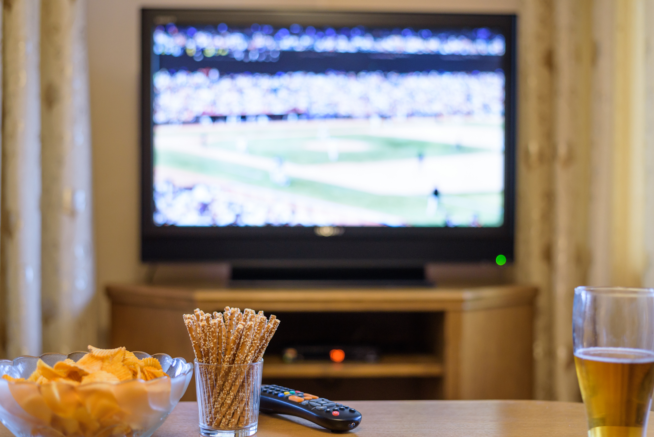 Television, TV watching (baseball match) with snacks and alcohol lying on table